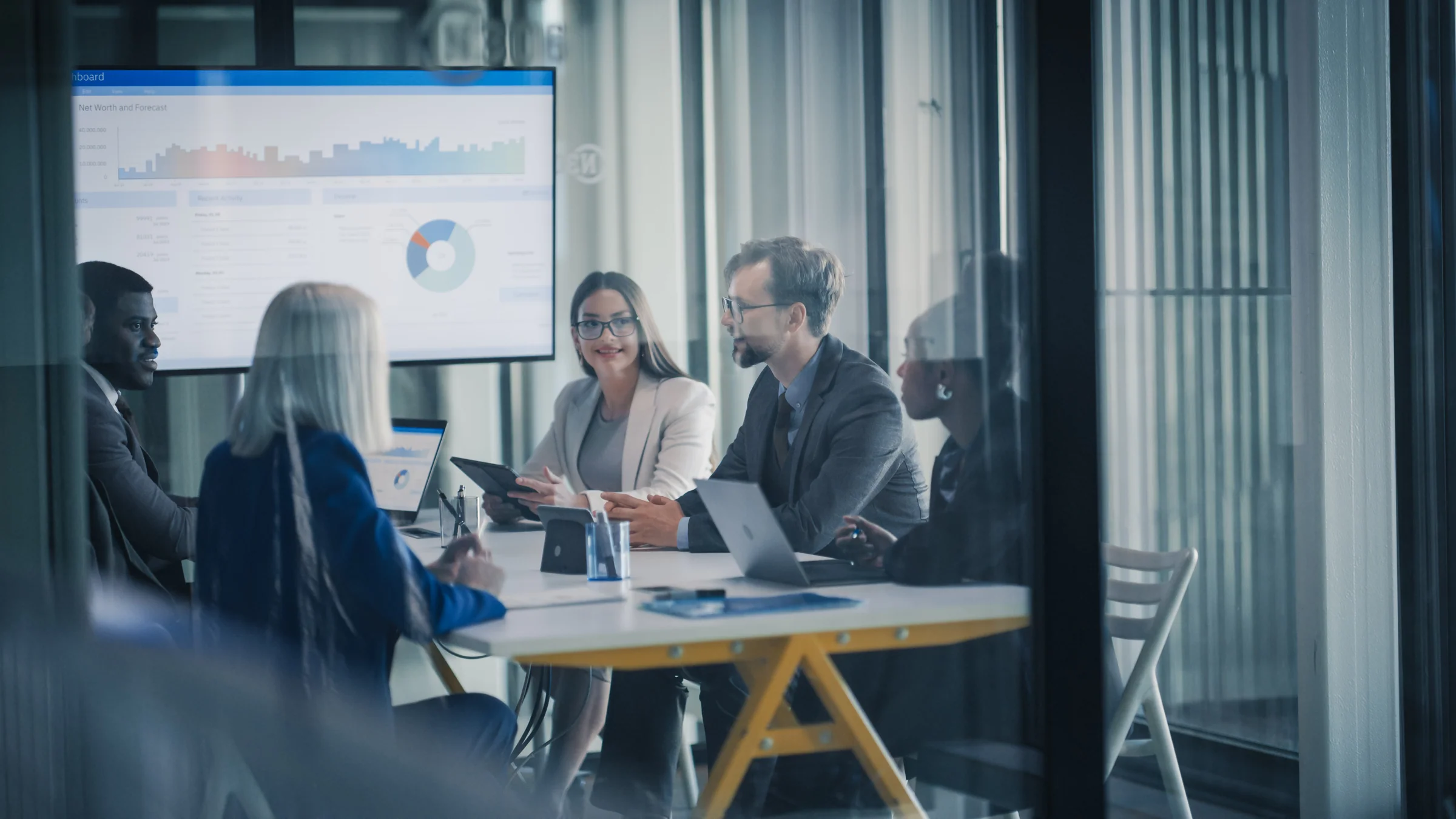 Senior executives reviewing an acquisition strategy in a modern boardroom.